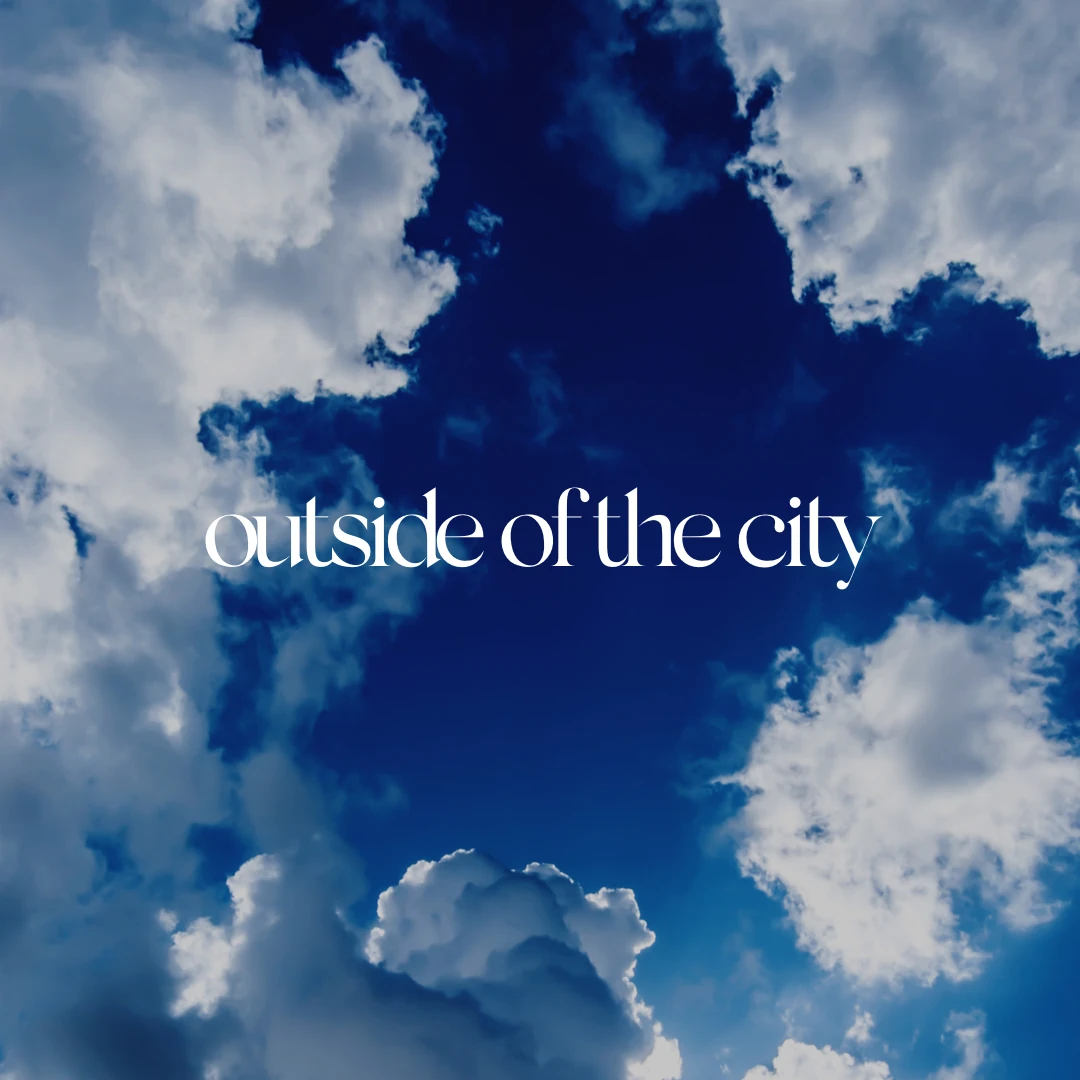 White “outside of the city” lettering over a deep blue sky of clouds